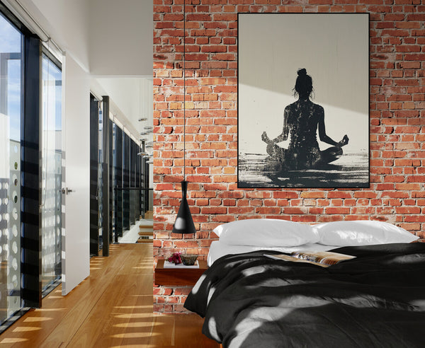 Chambre moderne avec un mur en briques apparentes, lit aux draps noirs et blancs, et un tableau représentant une silhouette féminine en position de méditation. La lumière naturelle met en valeur l’ambiance zen et urbaine de cet appartement.