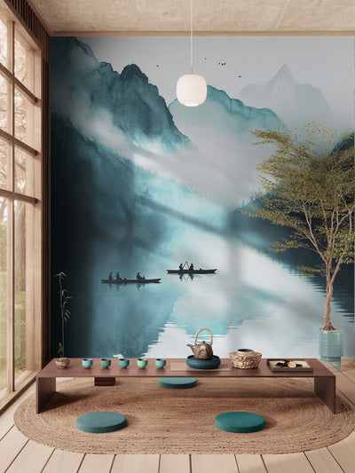 Salon d’inspiration japonaise avec un décor mural représentant un paysage de montagnes brumeuses et de barques sur un lac. L’espace est aménagé avec une table basse en bois, des coussins ronds turquoise, un tapis tressé et un service à thé, créant une ambiance zen et paisible propice à la méditation ou à la cérémonie du thé.