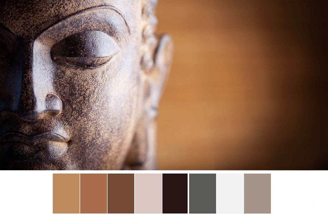 Visage sculpté de Bouddha en gros plan, dans des tons bruns, accompagné d’une palette de couleurs neutres.
