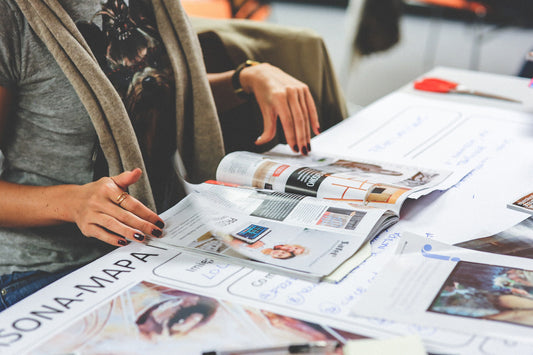 une personne en train de feuilleter des magazines sur une table, mettant en avant des pages illustrées avec des images de design, de décoration ou de publicité