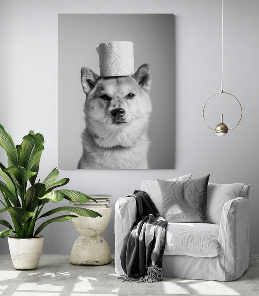 pièce de vie, fauteuil confortable, coussin et plaid gris, table d'appoint moderne blanche, grande plante verte, salle lumineuse, lumière en suspension, mur gris clair, tableau chien.