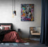 Chambre parentale, grand lit double, draps rouge et noir, tapis originale, fauteuil en metal noir, luminaire en suspension, mur blanc, grand rideau bleu nuit, affiche de Marylin monore.