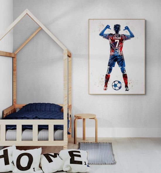 Une chambre d'enfant avec un lit en forme de maison, des jouets en bois sur le sol, et un poster encadrer personnalisé avec un joueur de football nommé "ETHAN" accroché au mur.