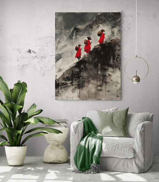 Le tableau de trois moines en robes rouges, accroché sur un mur gris clair, apporte une ambiance zen et contemplative. Il est entouré d'une grande plante verte, d'une petite table en pierre blanche avec des livres, et d'un fauteuil blanc confortable avec un plaid vert. Une suspension dorée ajoute une touche moderne à cet espace harmonieux et apaisant.