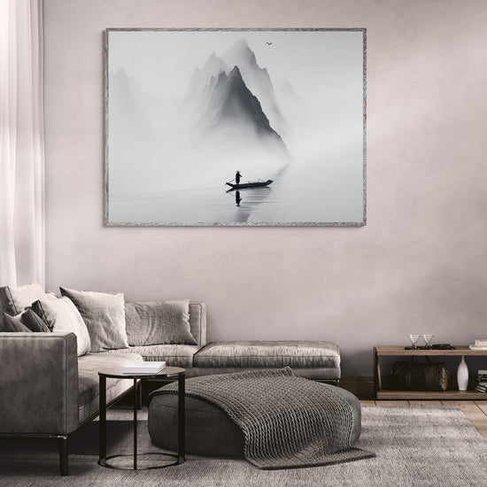 Déco mural zen représentant un pêcheur solitaire sur une barque devant des montagnes embrumées, accroché au-dessus d’un canapé d'angle gris dans un salon moderne avec table basse design et tapis gris