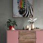 Le tableau du zèbre est le point focal au-dessus d'une console moderne rose et bois, dans un espace au design contemporain avec des touches de végétation.