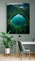 mage représentant une forêt dense entourant un lac turquoise, affichée dans un intérieur avec une chaise verte moderne et une grande plante d'intérieur