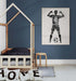 une chambre d'enfant décorée de manière moderne et épurée. Sur le mur, un grand tableau personnalisé représente un joueur de football, vu de dos, avec le prénom "Adam" et le numéro 10 sur son maillot. Le joueur lève les bras en signe de victoire. Le lit en bois simple et des coussins portant les lettres du mot "HOME" complètent l'ambiance chaleureuse et sportive de la pièce.