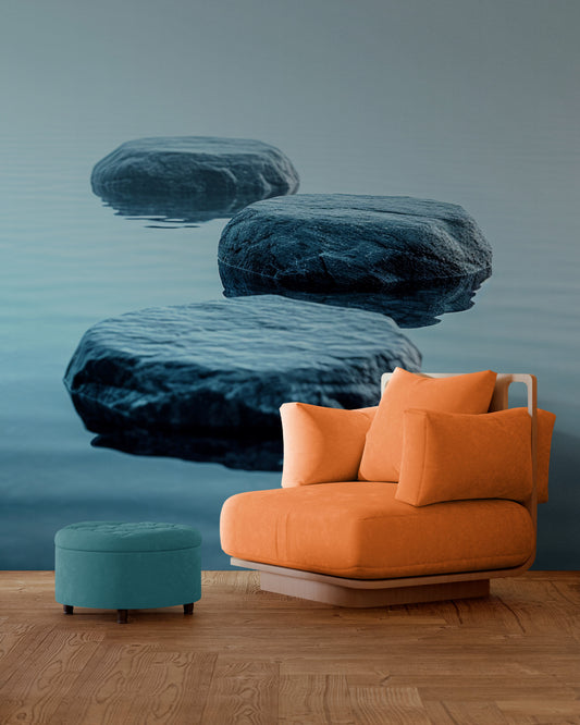 Un fauteuil orange vif posé devant une tapisserie panoramique représentant de grandes pierres flottant sur une eau calme, créant un contraste chaleureux et zen.