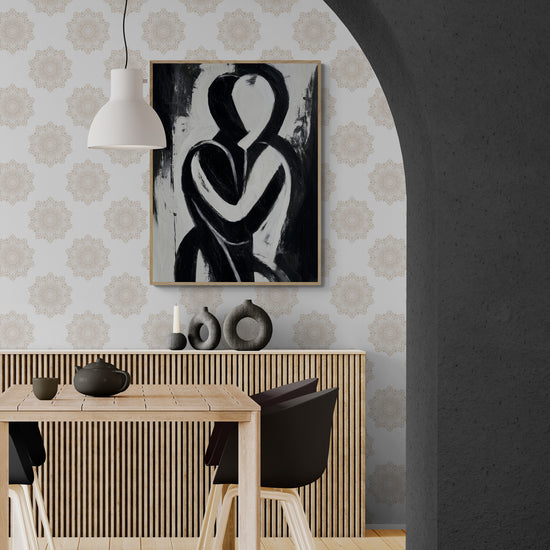 salle à manger moderne au style naturel, décorée d’un tableau abstrait noir et blanc représentant deux silhouettes entrelacées. Le mur à motif beige apporte une touche élégante et harmonieuse, tandis que les chaises noires et la table en bois clair créent un contraste chaleureux. Cette scène évoque une ambiance contemporaine, apaisante et raffinée, idéale pour un intérieur à la fois design et convivial.