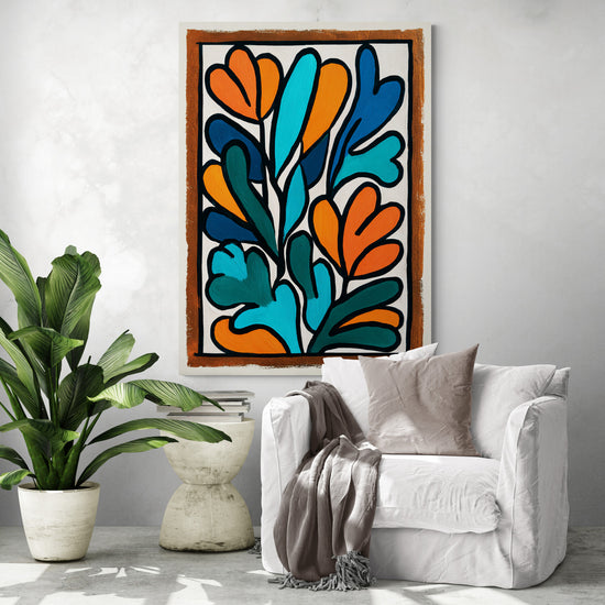 Un coin salon cosy avec fauteuil blanc, coussin taupe, grande plante verte et un tableau aux formes végétales colorées accroché au mur.