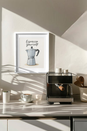 Décoration murale dans une cuisine moderne avec un tableau illustrant une cafetière italienne et l’inscription « Espresso Yourself », placé dans un cadre blanc au-dessus d’une machine à café, entouré de tasses et accessoires en bois.