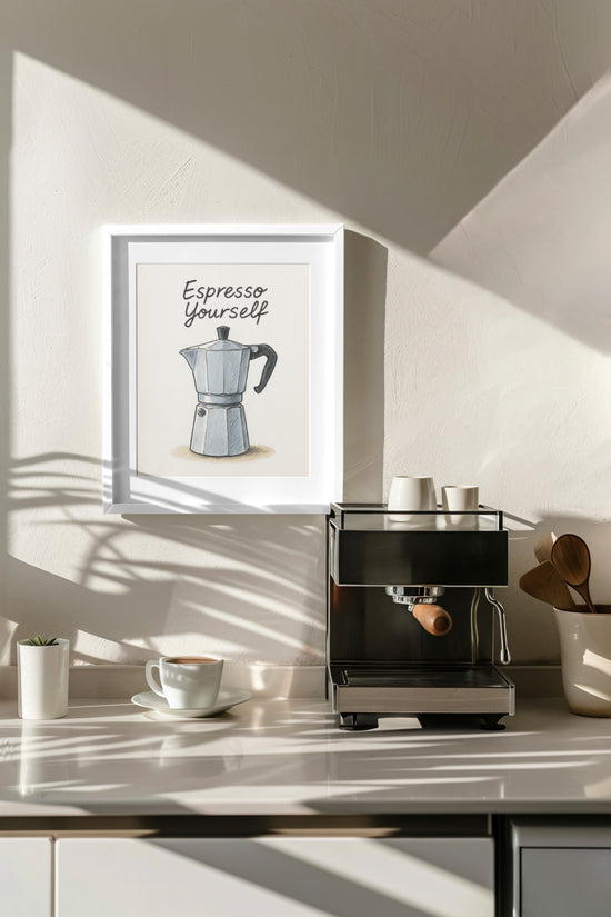 Décoration murale dans une cuisine moderne avec un tableau illustrant une cafetière italienne et l’inscription « Espresso Yourself », placé dans un cadre blanc au-dessus d’une machine à café, entouré de tasses et accessoires en bois.