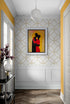 couloir Décoration intérieure Tableau d'art abstrait Silhouettes embrassées Couleurs chaudes (orange, rouge, jaune) Ambiance intime et accueillante Papier peint avec motifs circulaires dorés Murs blancs avec moulures Plafond avec luminaire suspendu Vase avec fleurs violettes Table console noire avec éléments décoratifs Plancher en bois à chevrons Éléments décoratifs modernes et élégants Atmosphère harmonieuse et chaleureuse