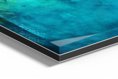 Zoom sur un tableau imprimé sur support métal et plexiglass, mettant en valeur la brillance et la profondeur des couleurs bleu turquoise, avec des reflets lumineux sur la surface vitrifiée.