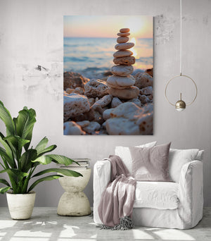 Toile de galets zen installée dans un salon lumineux, au mur blanc texturé, près d’un fauteuil blanc et de plantes vertes.