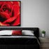 Décoration murale romantique avec un tableau de rose rouge au-dessus d’un lit moderne, ambiance élégante et sensuelle pour chambre à coucher.