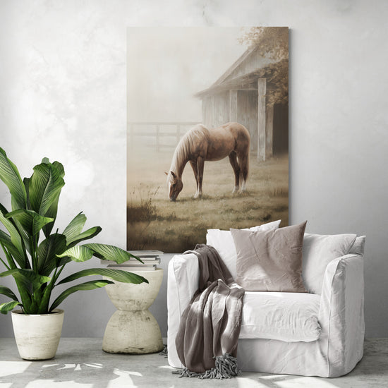 Grand tableau cheval de campagne au-dessus d’un fauteuil blanc ; grange brumeuse, déco rustique chic, atmosphère sereine.
