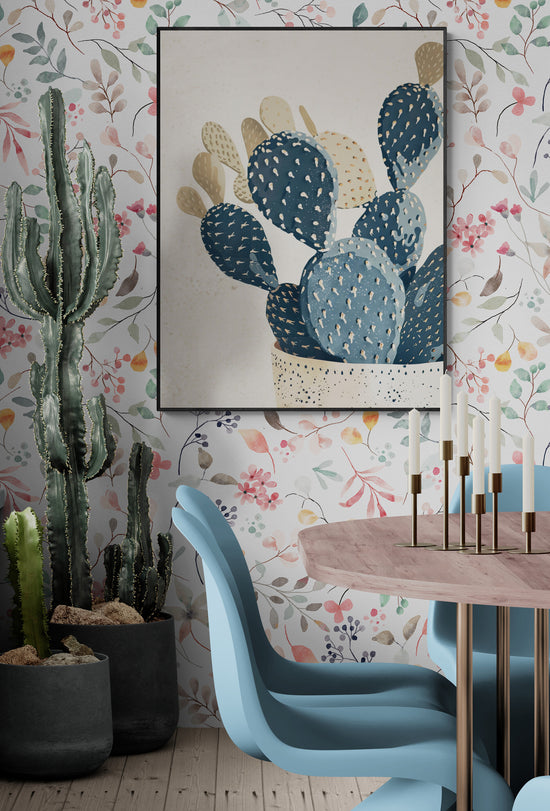 Tableau cactus stylisé Papier peint floral Cactus en pot Chaises modernes bleu clair Table en bois et métal doré Bougeoirs dorés Sol en bois clair Éclairage naturel Style éclectique et moderne Ambiance botanique