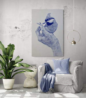 Toile murale représentant une main stylisée tenant un oiseau, accrochée dans un salon épuré avec fauteuil blanc, coussin bleu clair et plante verte.