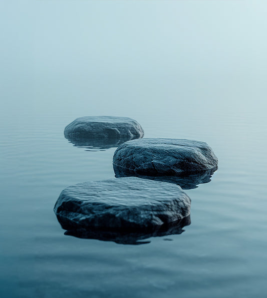 Un papier peint panoramique représentant trois galets posés sur une eau calme et paisible, avec une brume douce à l'arrière-plan. Les couleurs bleutées et apaisantes créent une atmosphère zen