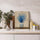 Toile canvas décorative représentant un vase moderne rempli de fleurs bleues séchées sur fond beige texturé, posée sur un plan de travail de cuisine contemporaine. Le tableau floral aux tons naturels et bleus profonds apporte une touche élégante et apaisante à une décoration minimaliste avec mur effet béton clair, accessoires en céramique et éléments en métal argenté. Une œuvre murale idéale pour sublimer une cuisine moderne avec une ambiance douce, naturelle et raffinée.