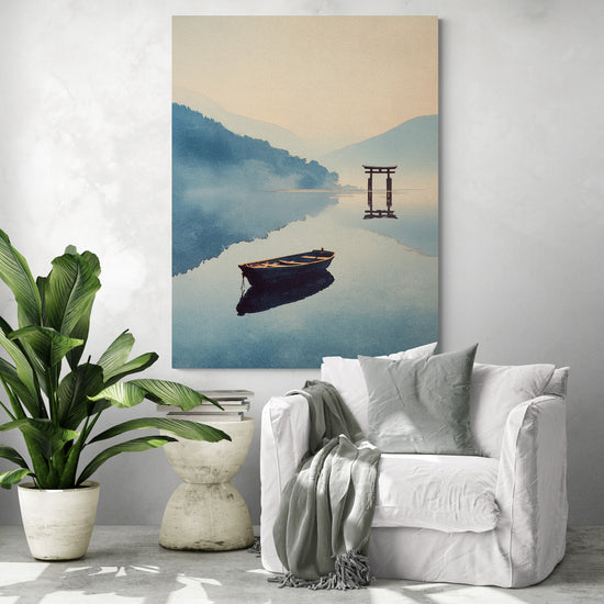 Grande toile murale japonaise représentant une barque solitaire flottant sur un lac calme face à un torii traditionnel, accrochée dans un salon moderne avec fauteuil blanc, coussin décoratif, plaid gris, plante verte tropicale et table basse en béton design