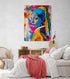 chambre parentale, lit double, draps blanc, plaid rouge, fauteuil en osier, commode en bois, affiche portrait femme.