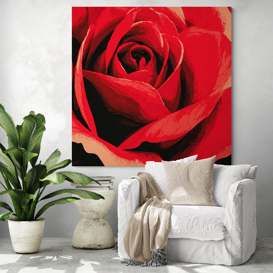 Grand tableau mural de rose rouge installé dans un salon moderne avec fauteuil blanc et plante verte, apportant une touche d’amour et de romantisme