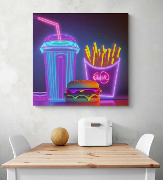 Sur un mur blanc de cuisine, il y a un tableau cuisine originale au look vintage. Sur cette toile une illustration d’un menu de fast-food. Ce tableau cuisine reflète une ambiance rétro qui s’inspire des panneaux signalétiques effet néon de grandes chaînes de restauration rapide dans l'Amérique des années cinquante. Au-dessous une table en bois et deux chaises blanches. Une corbeille à pain en métal blanc et un melon sont sur le dessus de la table.