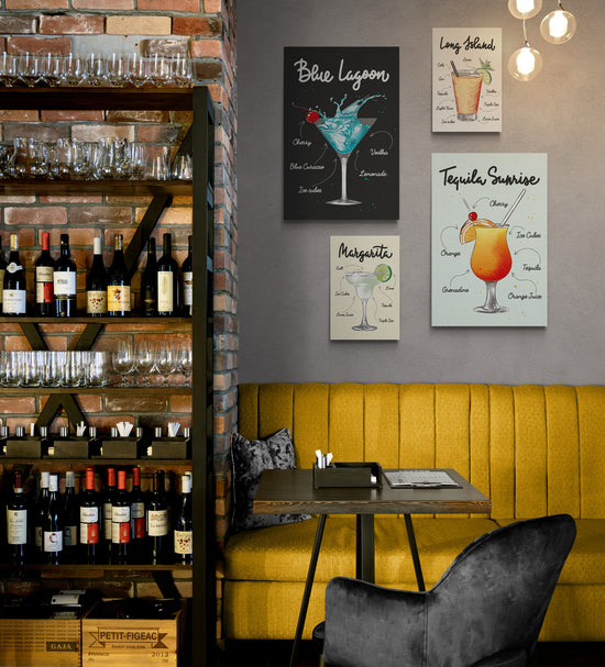 Un restaurant avec sur la droite une étagère pleine de bouteilles de vin et sur la gauche au-dessus d’une banquette en daim jaune, une décoration avec plusieurs tableaux de la même collection accroché au mur $. Sur chaque toile un verre de cocktail différent et les ingrédients nécessaires à sa réalisation